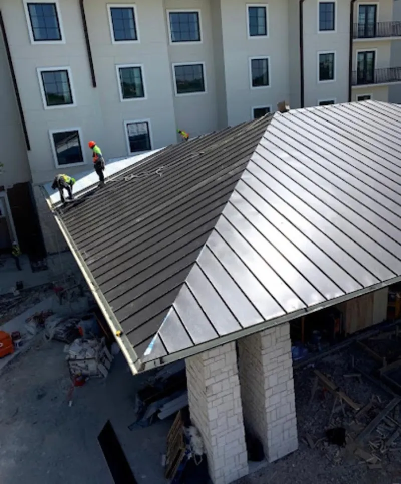 Crew installing standing seam metal roof panels on a commercial project in Barrington